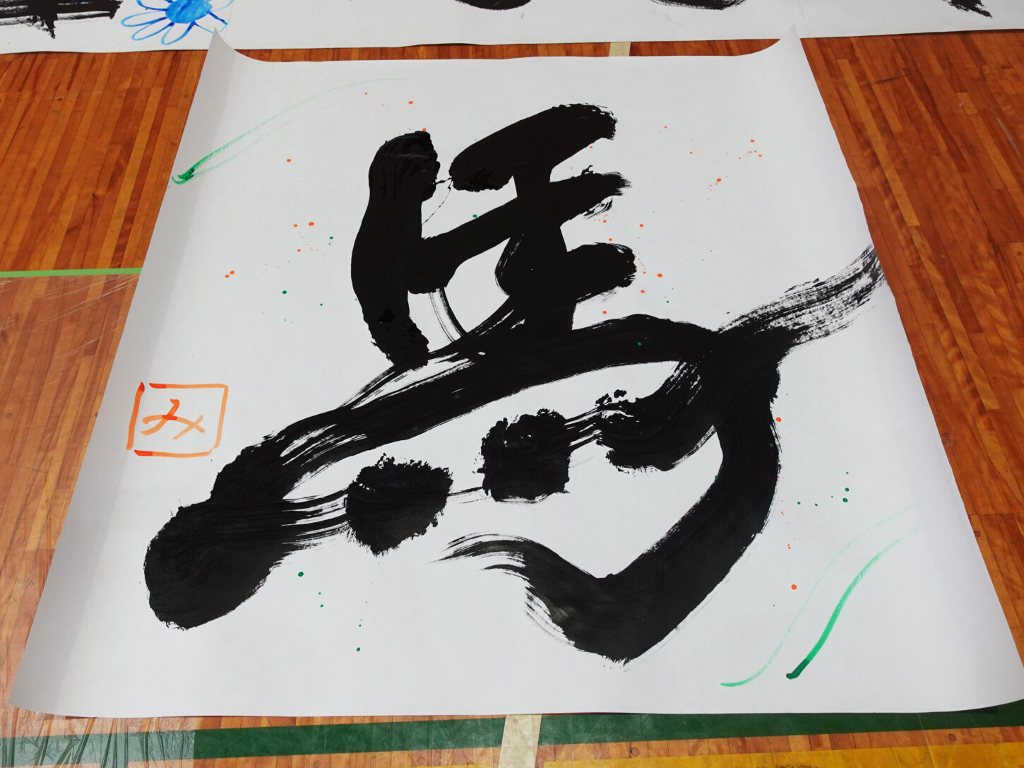 国立磐梯青少年交流の家「スマイルばんせい」で、親子が床に広げた大きな紙へ大胆に文字を書く書道パフォーマンス体験の様子。