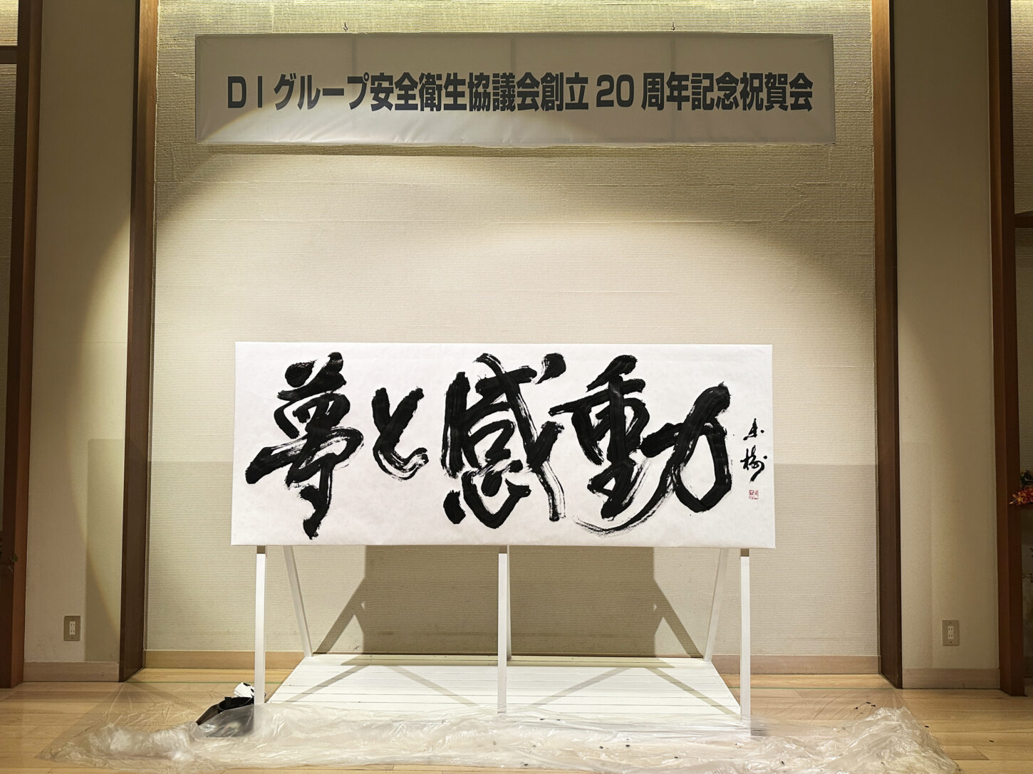 書家・根本みきが「DIグループ安全衛生協議会 創立20周年記念祝賀会」で、DIグループ代表・小板橋社長のモットー「夢と感動」を力強く揮毫する書道パフォーマンスを披露。参加者の夢が実り、感動が広がるよう願いを込めた作品。