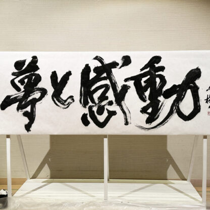 書家・根本みきが「DIグループ安全衛生協議会 創立20周年記念祝賀会」で、DIグループ代表・小板橋社長のモットー「夢と感動」を力強く揮毫する書道パフォーマンスを披露。参加者の夢が実り、感動が広がるよう願いを込めた作品。