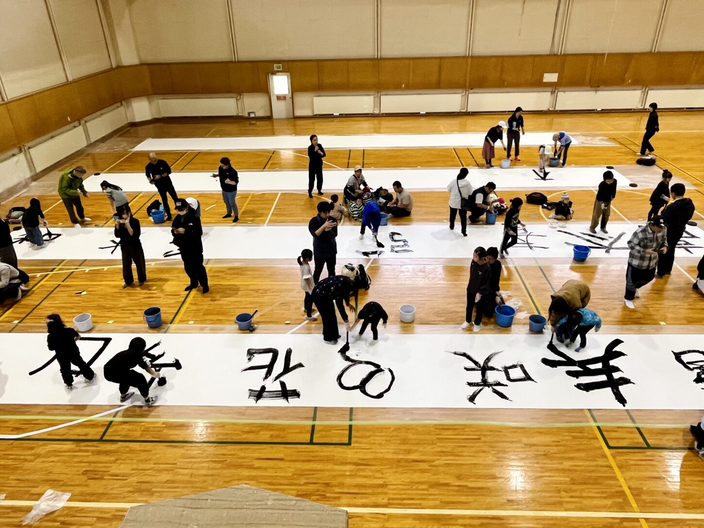 国立磐梯青少年交流の家で行われた「スマイルばんせい」で、親子が大きな紙に筆を使って文字を書く書道パフォーマンス体験。