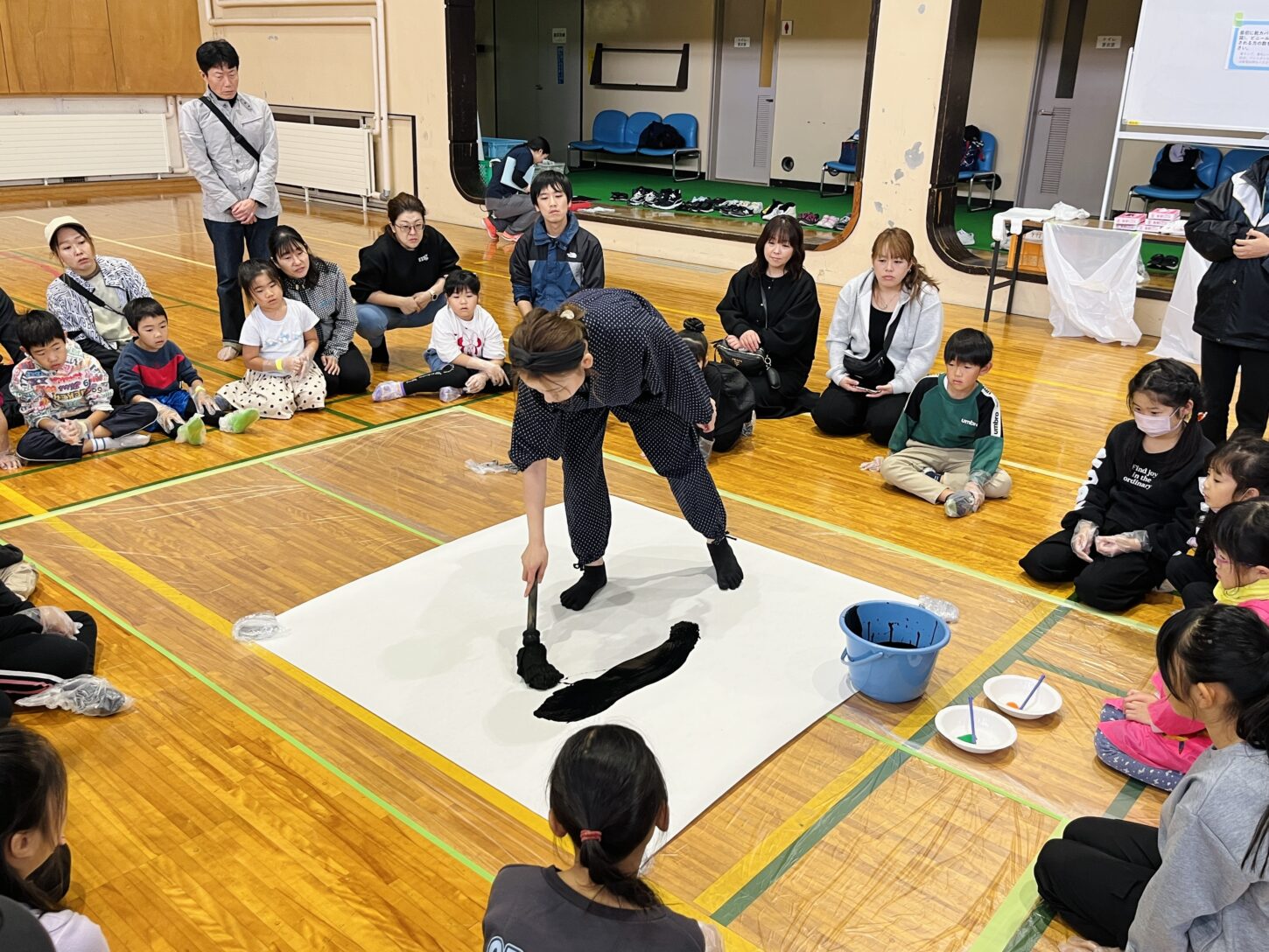 国立磐梯青少年交流の家で行われた「スマイルばんせい」で、親子が大きな紙に筆を使って文字を書く書道パフォーマンス体験。