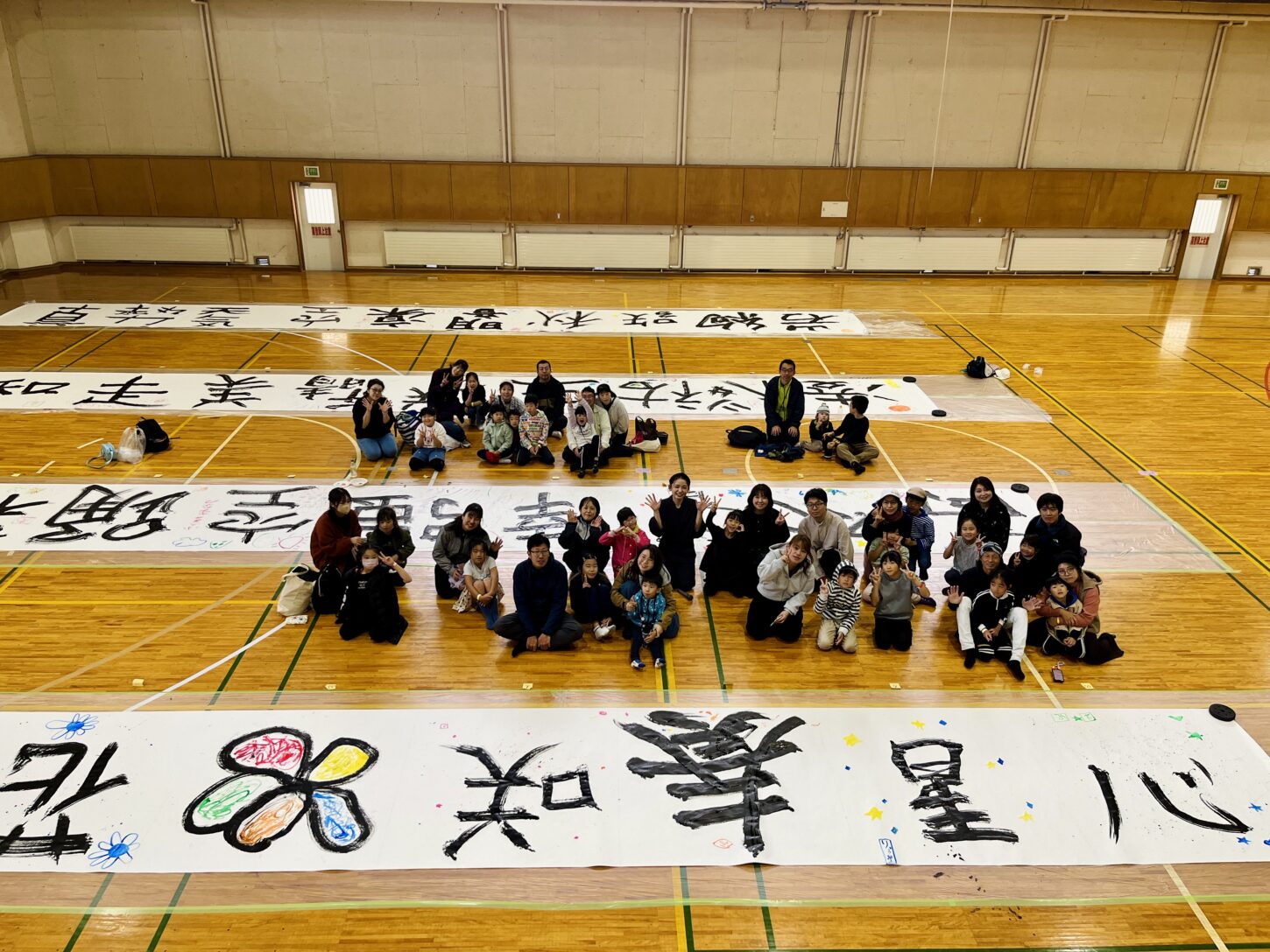 国立磐梯青少年交流の家で行われた「スマイルばんせい」で、親子が大きな紙に筆を使って文字を書く書道パフォーマンス体験。