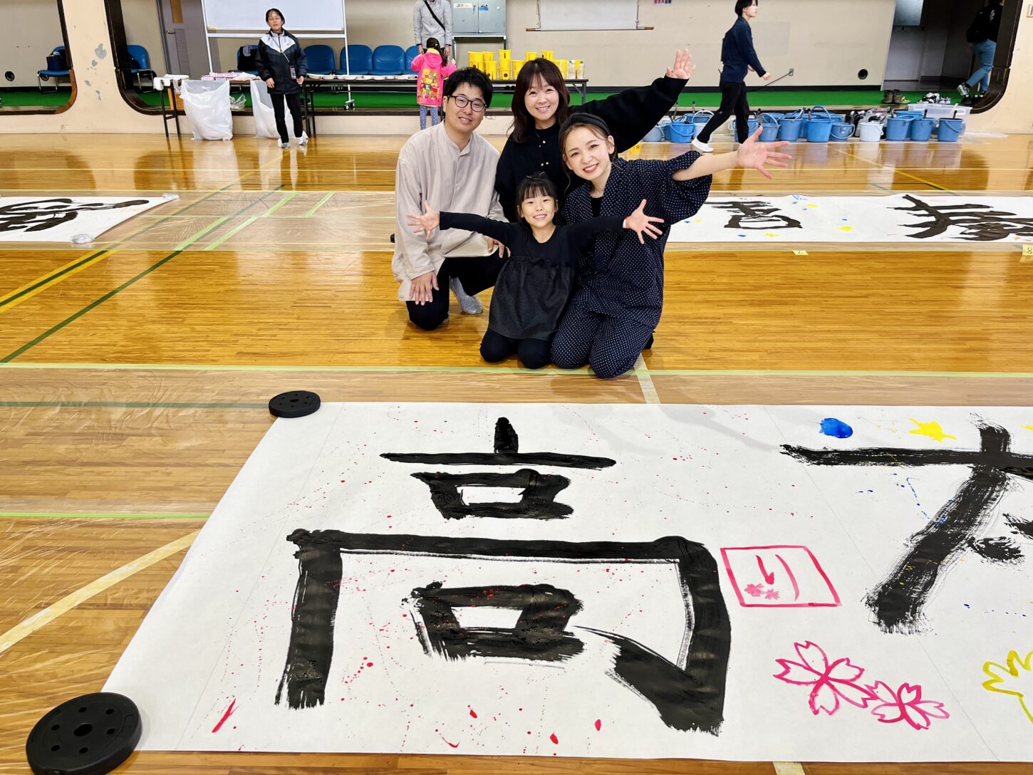 国立磐梯青少年交流の家で行われた「スマイルばんせい」で、親子が大きな紙に筆を使って文字を書く書道パフォーマンス体験。