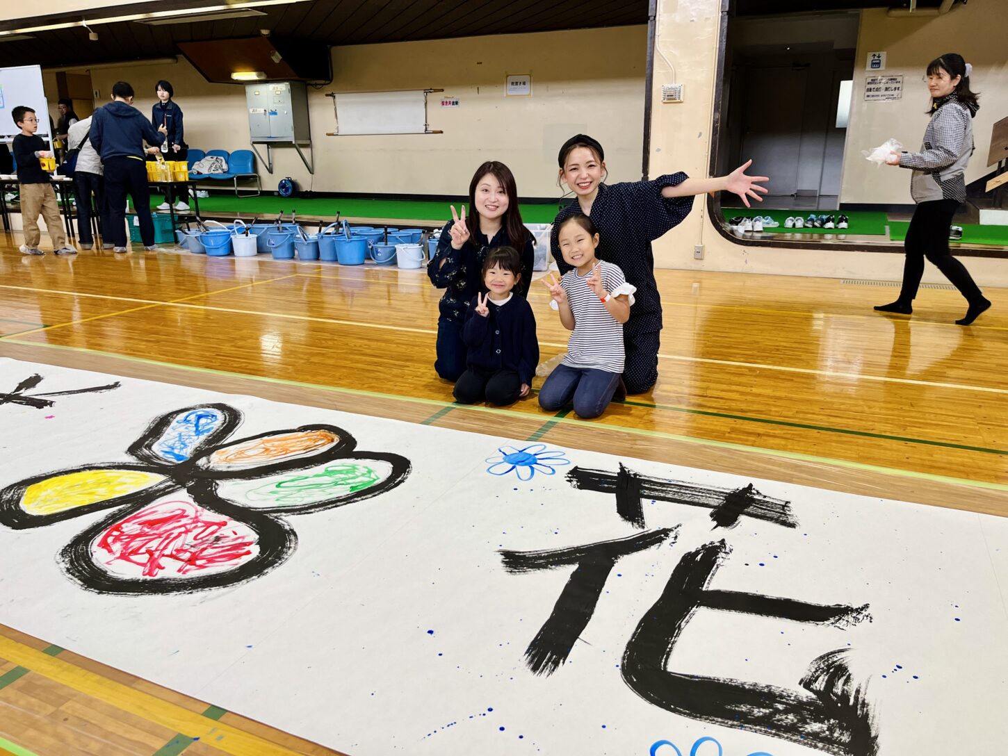 国立磐梯青少年交流の家で行われた「スマイルばんせい」で、親子が大きな紙に筆を使って文字を書く書道パフォーマンス体験。