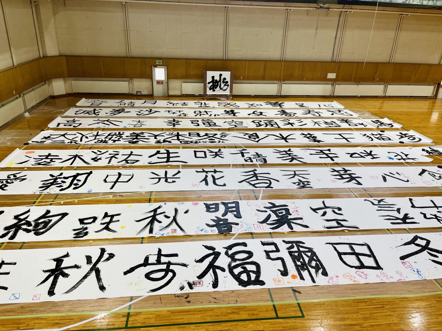 国立磐梯青少年交流の家で行われた「スマイルばんせい」で、親子が大きな紙に筆を使って文字を書く書道パフォーマンス体験。