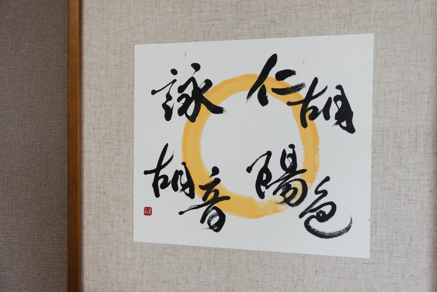 木目調フレームに額装された、書家・根本みきによるアート書道作品。黄金色の円相の上に、お子様４名の名を柔らかくつなぐように書き上げ、家族の温かなつながりと印象を表現した一作。