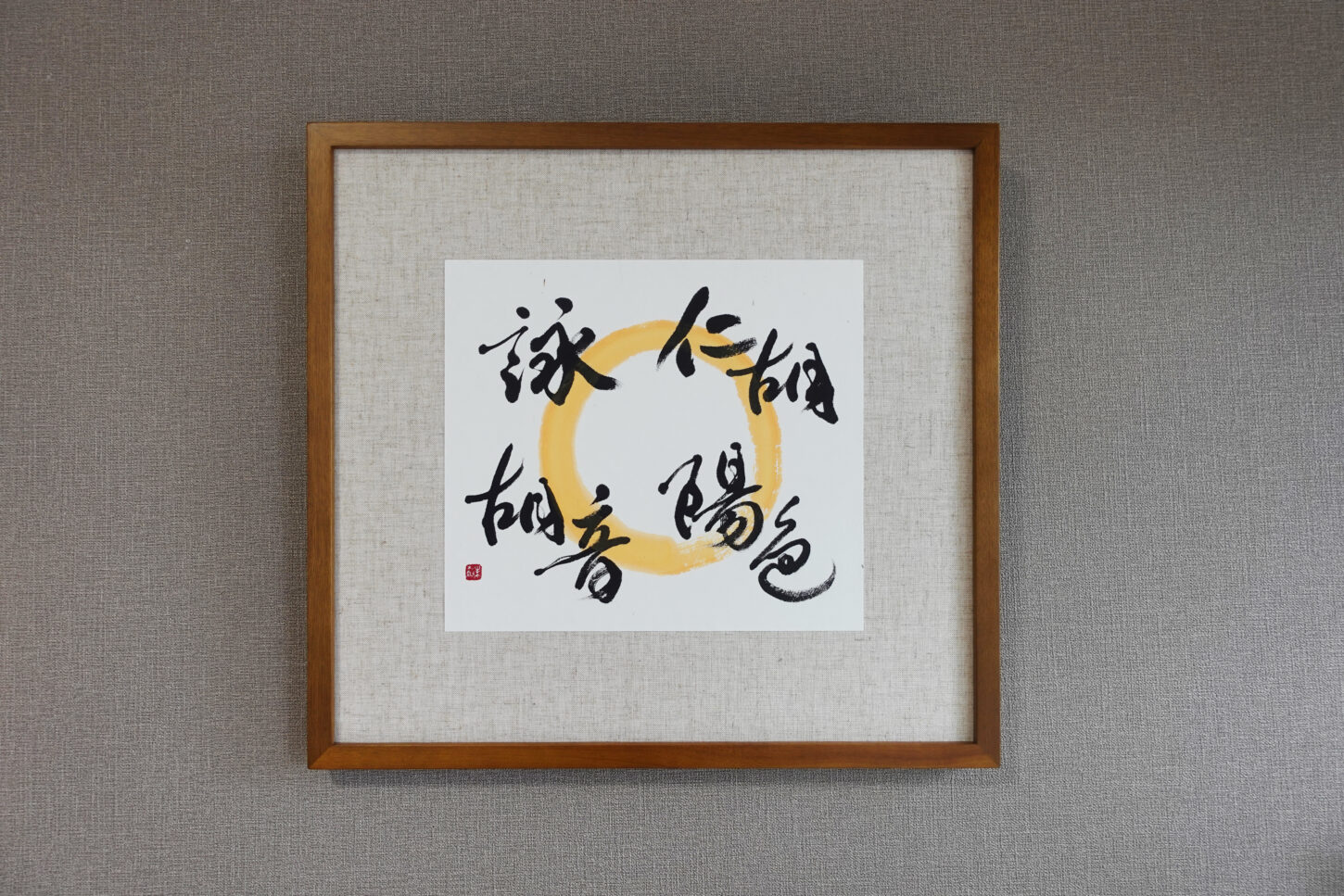 木目調フレームに額装された、書家・根本みきによるアート書道作品。黄金色の円相の上に、お子様４名の名を柔らかくつなぐように書き上げ、家族の温かなつながりと印象を表現した一作。