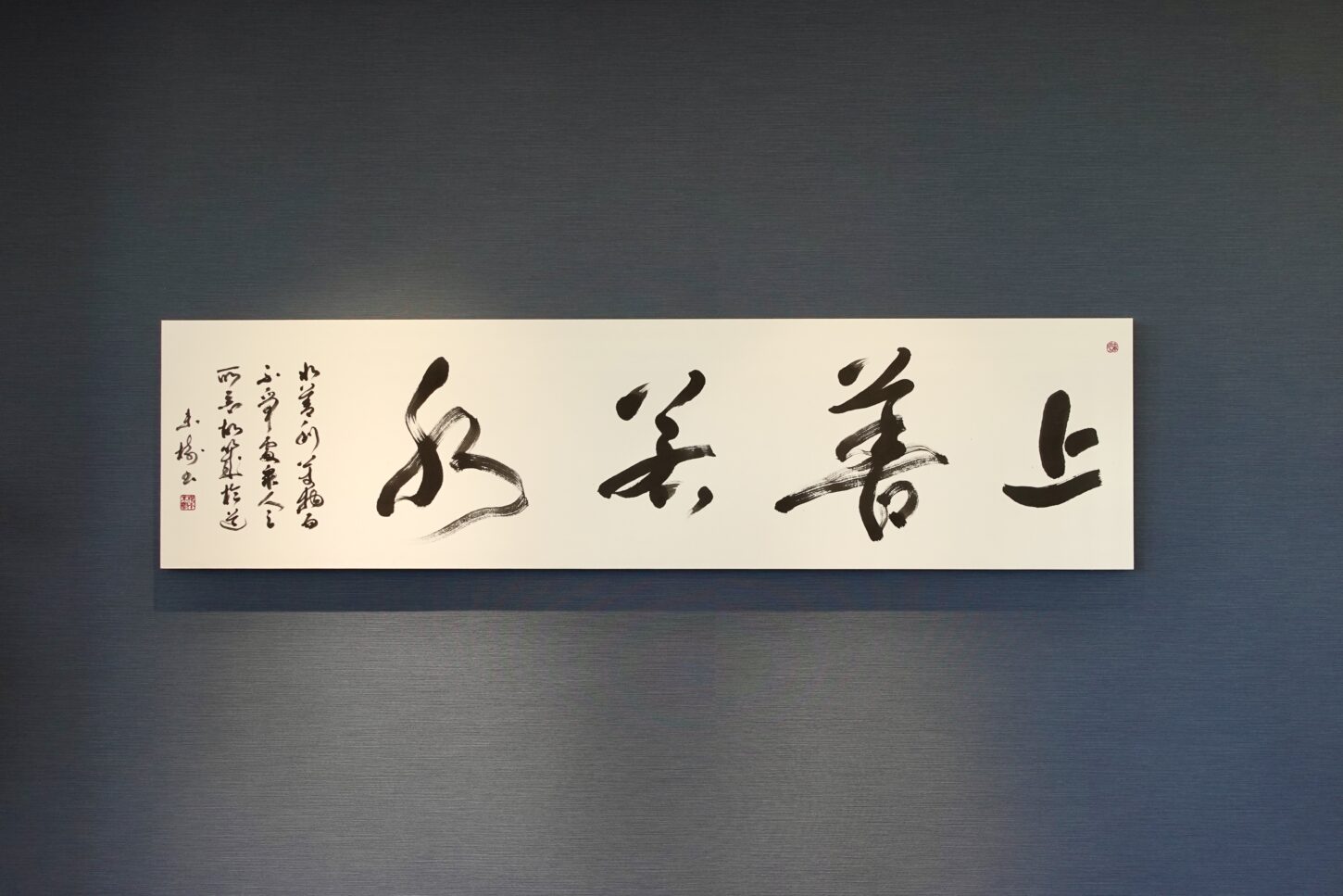 上善若水｜株式会社東栄住宅ご依頼の書道作品。老子の言葉をテーマに、水の流れを想起させる筆致で揮毫。社長室の空間と調和するパネル表装で仕上げた、書家・根本みきによる企業向けオーダーメイド書作品。